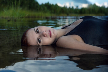 close up portrait of fashionable beautiful girl lying in water with reflection