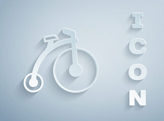 Paper cut Vintage bicycle with one big wheel and one small icon isolated on grey background. Bike public transportation sign. Paper art style. Vector