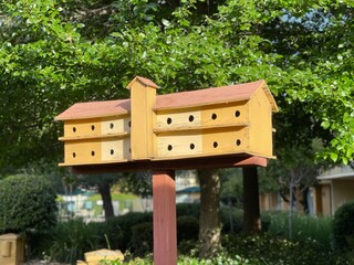 Large birdhouse with lush green foliage in the background