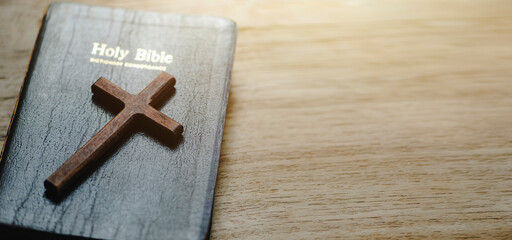 A cross with the holy bible is placed on a wooden table on Sunday. worship prayer and bible study concept