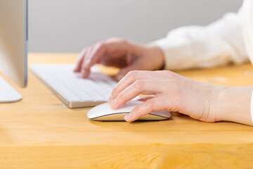 Close-up of young female hands pressing keyboard buttons and using a mouse