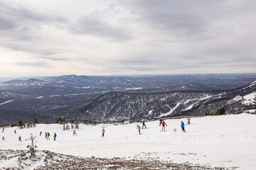 Fototapeta na wymiar ski resort with mountain views of medium height, skiers and snowboarders going downhill