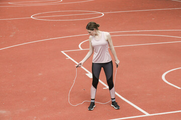 Young woman skipping jump rope on a sport field
