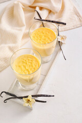 Board with tasty vanilla pudding on light background