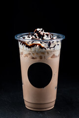 Chocolate milkshake covered with whipped cream in plastic glass isolated on white background