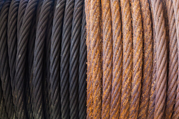 A rusty steel cable wound on a winch next to a greased new cable.
