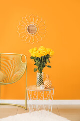 Vase with yellow roses on table and armchair near color wall