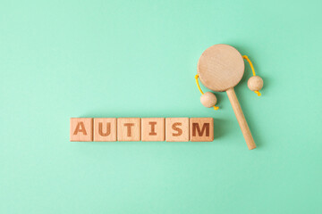 Word AUTISM and rattle on color background