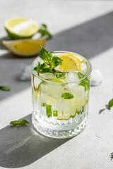 Summer healthy lemonade, cocktails of citrus infused water or mojitos, with lime, lemon , ice and mint, diet detox beverages, in glasses on gray background	