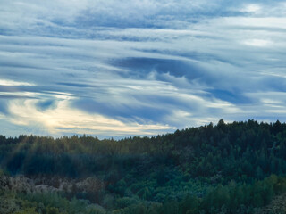Fototapeta na wymiar Epic cloudscape at sunset over forested mountain ridge