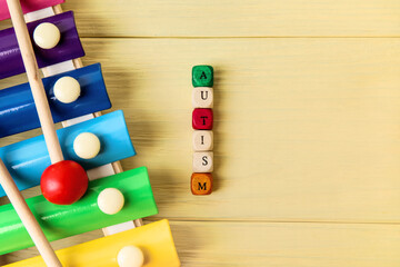 Word AUTISM and xylophone on color wooden background