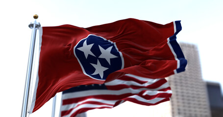 The flags of the Tennessee state and United States of America waving in the wind.