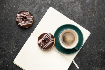 Cup of freshly brewed coffee and donuts on dark background