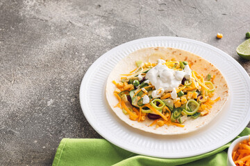 Plate with tasty taco and sauce on grunge background