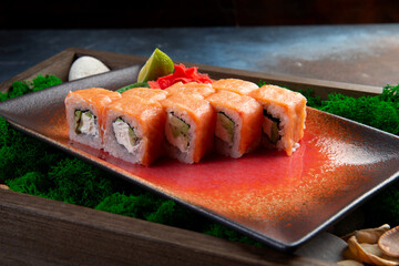 Classic Philadelphia sushi roll on a plate with wasabi, ginger, soy sauce