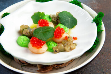 Scallops with caviar, microgreens and green sauce on a white plate.