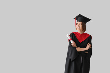 Female graduating student with diploma on light background