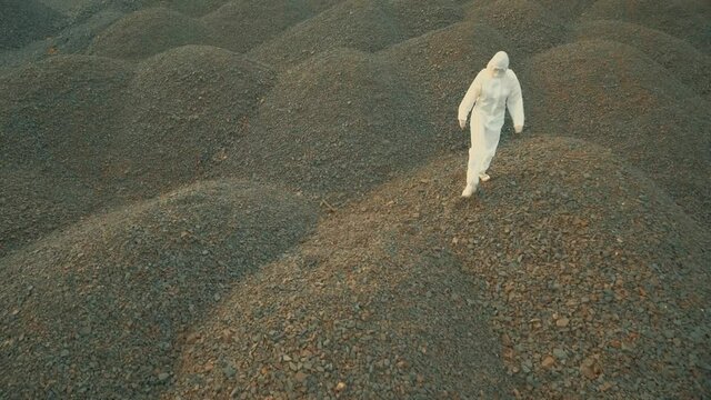 a man in a white bacteriological suit walks along the stone embankments. Drone shooting