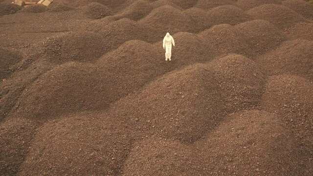 a man in a white bacteriological suit walks along the stone embankments. Drone shooting