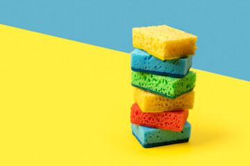 Creative layout with sponges for dishwashing on yellow and blue background