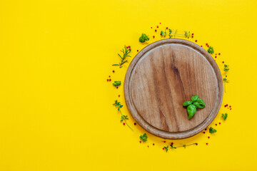 Seasonings on the wooden circle cutting board on the yellow background