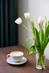 still life, a cup of cappuccino and white tulips in a glass vase on a wooden table, a copy of the space, a birthday gift for a girl, March 8, mother's day