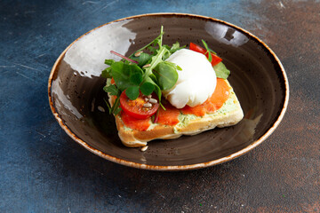 sandwich with poached egg, salmon and tomatoes in a plate.