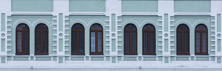 Three old windows on the facade of a green building