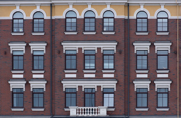 Fototapeta na wymiar Texture of the building with red brick and white decor on the windows.
