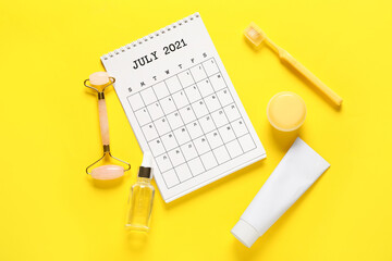 Calendar, accessories and cosmetics on color background