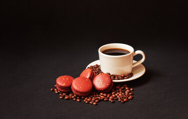 Coffee cup, chocolate macaroons and coffee beans on dark background