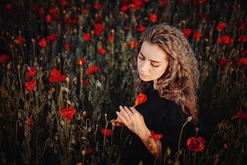 Naklejka premium Beautiful young woman with poppy in field
