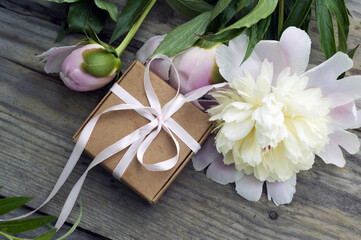 straw hat, pink peonies, gift box on wooden background