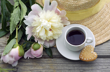 Obraz na płótnie Canvas pink peonies, a cup of coffee, cookies, a straw hat. romantic breakfast.