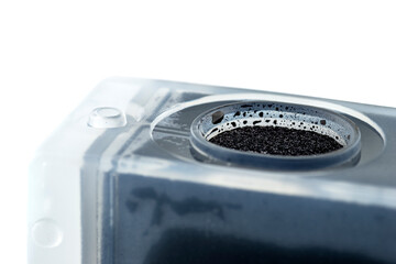 Macro photo of a black ink cartridge for a color printer, isolated on white background.