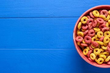 Bowl with cereal rings on color wooden background