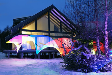 Winter modern house illuminated with abstract magic LED lights in blue winter evening