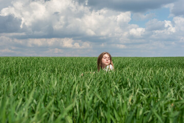 teenage girl in green grass, in the field, against the backdrop of a cloudy sky