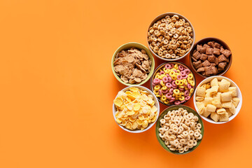 Bowls with different cereals on color background