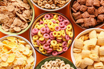 Bowls with different cereals on color background, closeup