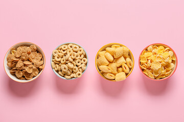 Bowls with different cereals on color background
