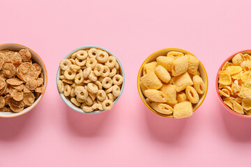 Bowls with different cereals on color background