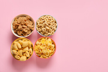 Bowls with different cereals on color background