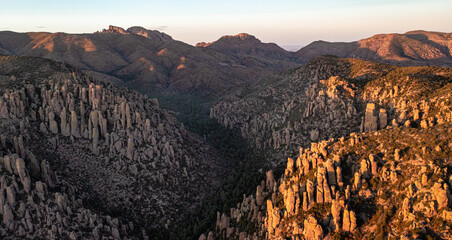 Aerial view of rock columns in a valley below a mountain at sunset in Arizona