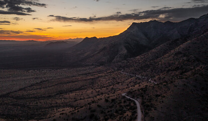 Sunset behind Arizona mountains with a road and several mountain peaks