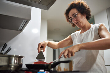 Woman cooking with a frying pan on the stove