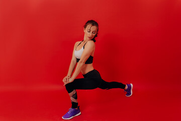 Fototapeta na wymiar Full-lenght studio portrait of woman in sport uniform stretching and doing exercises over isolated backdrop 