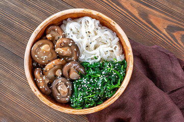 Fototapeta na wymiar Bowl with rice noodles, mushrooms and spinach
