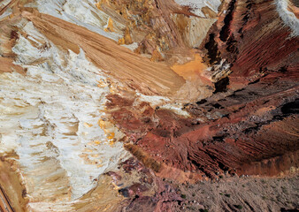 Aerial view of the inside of a mine in Arizona. Textured dirt in red, orange, white, and pink hues.