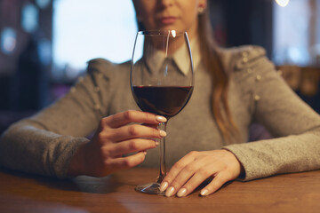 Hand of a young beautiful woman holding a glass of wine indoors of a stylish wine restaurant